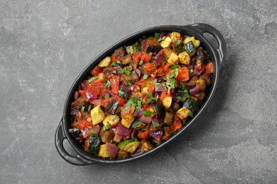 Photo of Dish with tasty ratatouille on grey textured table, top view