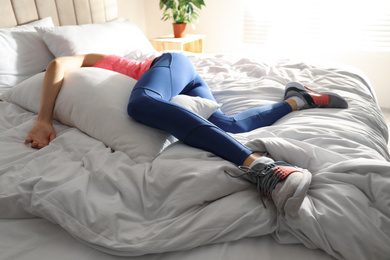 Photo of Lazy young woman sleeping on bed instead of morning training