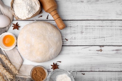 Fresh dough and ingredients on white wooden table, flat lay. Space for text