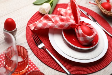Festive table setting with bunny ears made of red egg and napkin. Easter celebration