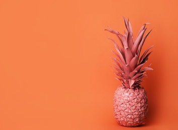 Coral painted pineapple on orange background. Space for text