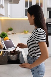 Woman looking at recipe on tablet while cooking in kitchen