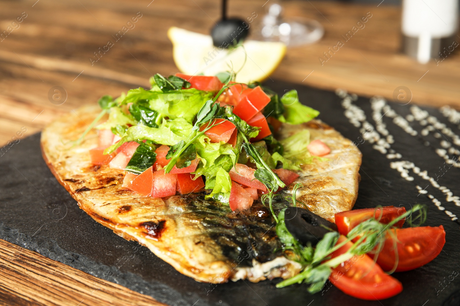 Photo of Delicious grilled fish served on wooden table, closeup