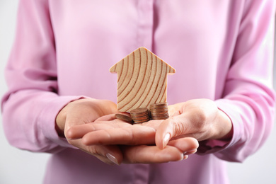 Woman holding house model and coins, closeup