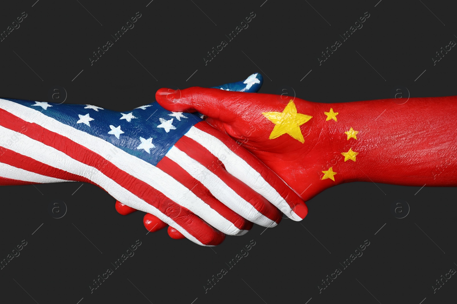 Photo of USA and China partnership. People shaking hands painted in flags on black background, closeup