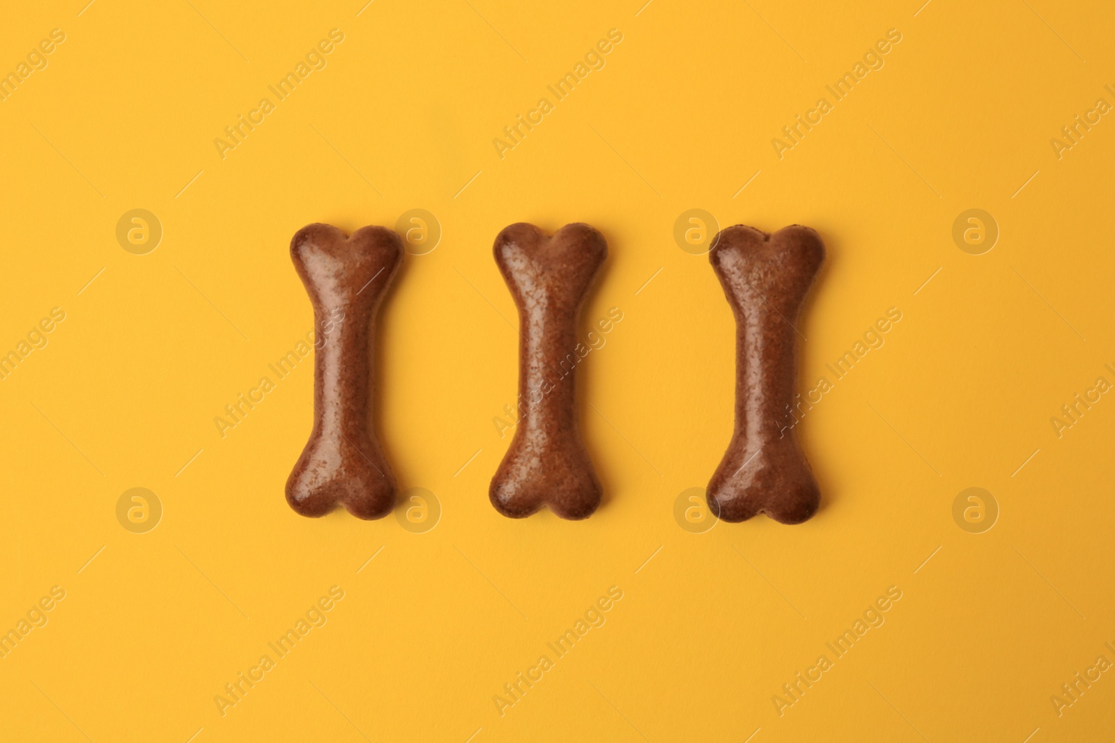 Photo of Bone shaped dog cookies on orange background, flat lay