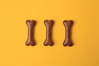 Bone shaped dog cookies on orange background, flat lay