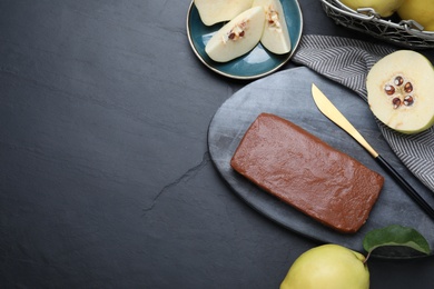 Photo of Flat lay composition with delicious quince paste on black table, space for text