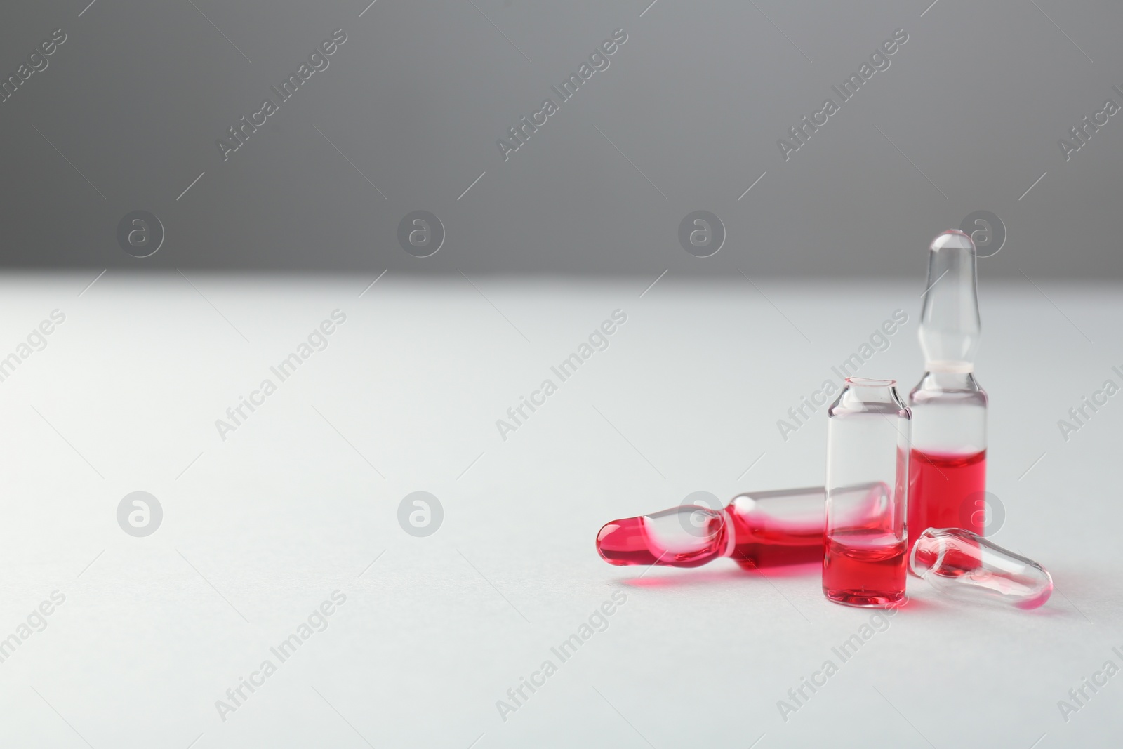 Photo of Glass ampoules with liquid on white background. Space for text