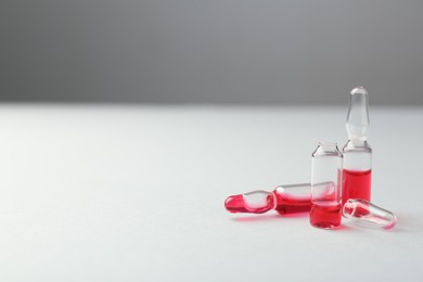 Photo of Glass ampoules with liquid on white background. Space for text