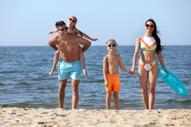 Photo of Happy family with inflatable ring on sandy beach near sea. Summer holidays