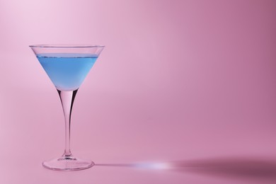 Photo of Martini glass with delicious cocktail on pink background, space for text