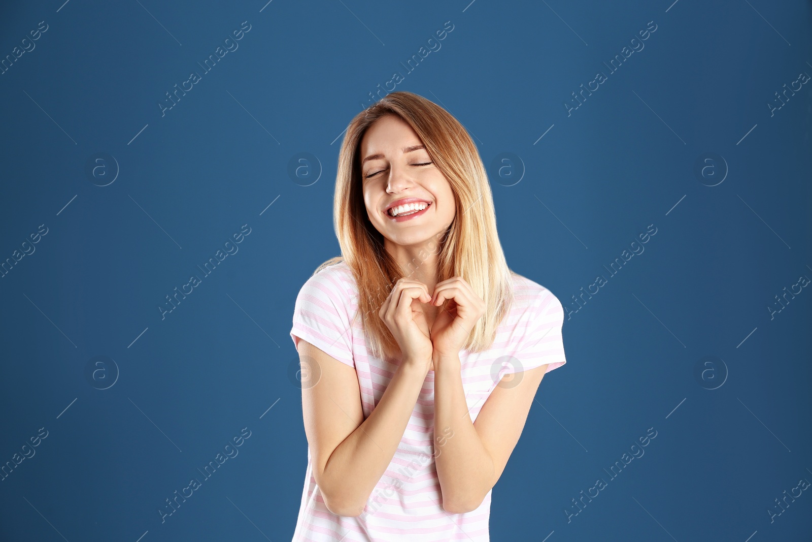 Photo of Portrait of pretty woman making heart with her hands on color background