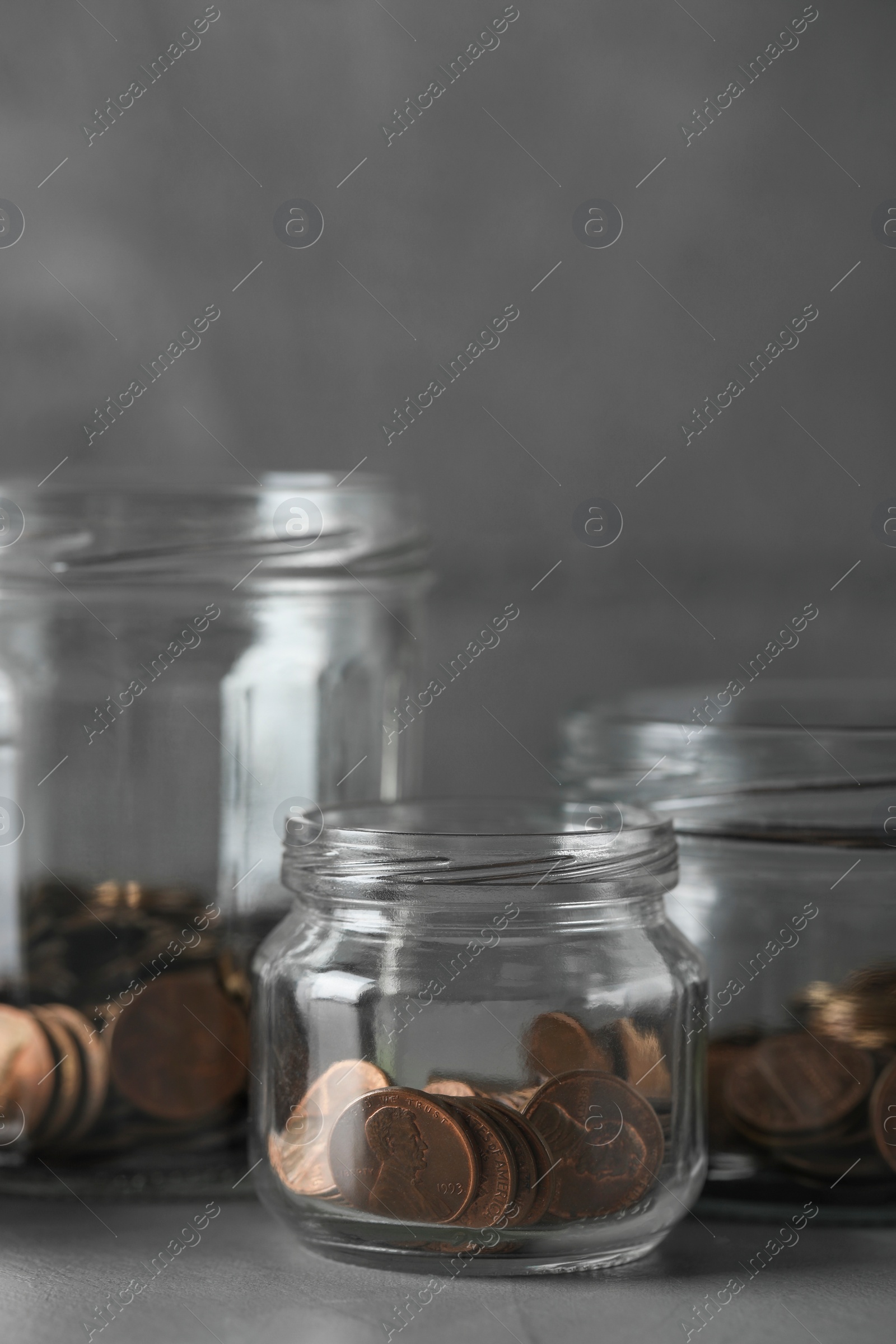 Photo of Glass jars with coins on grey table, closeup