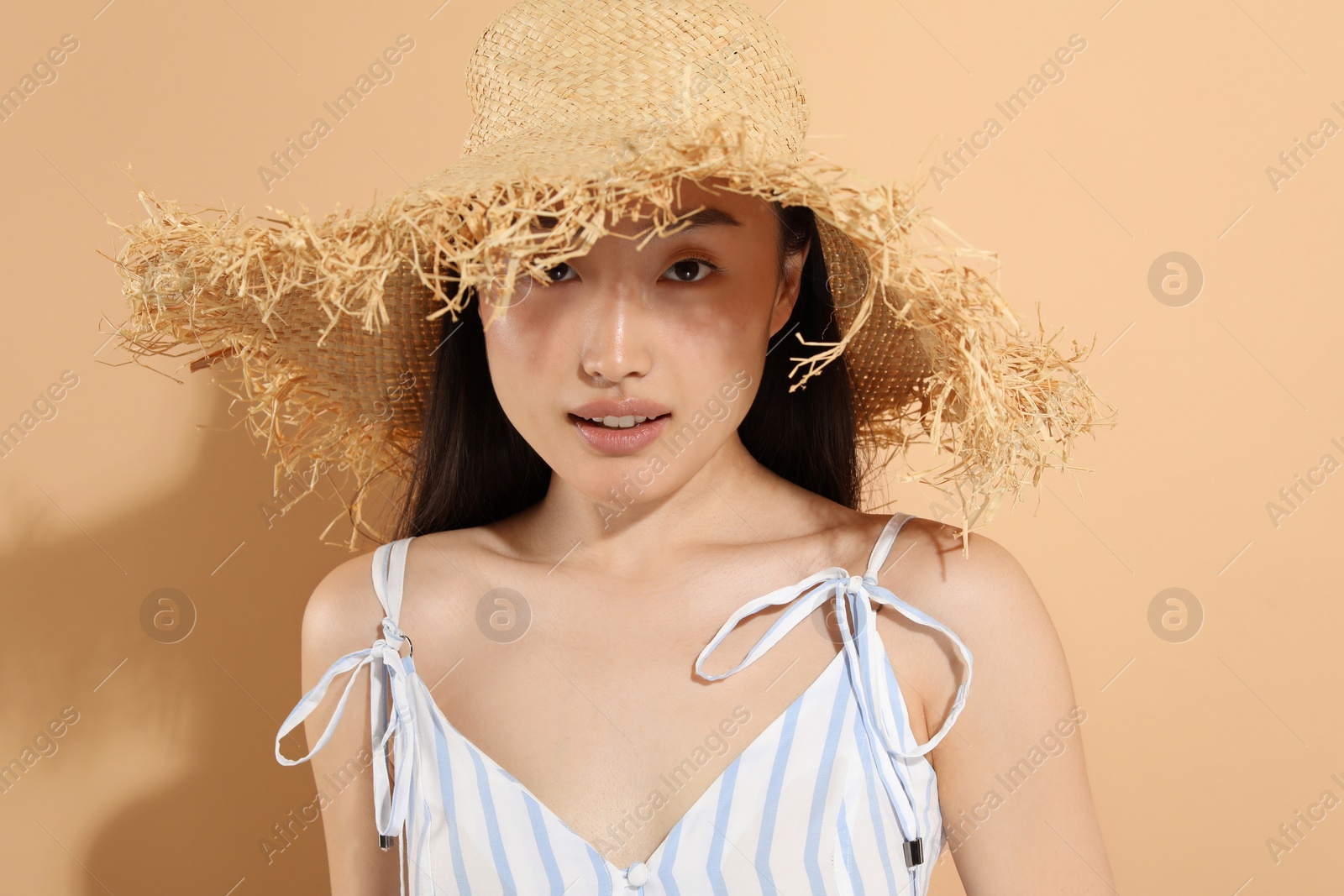 Photo of Beautiful young woman in straw hat on beige background