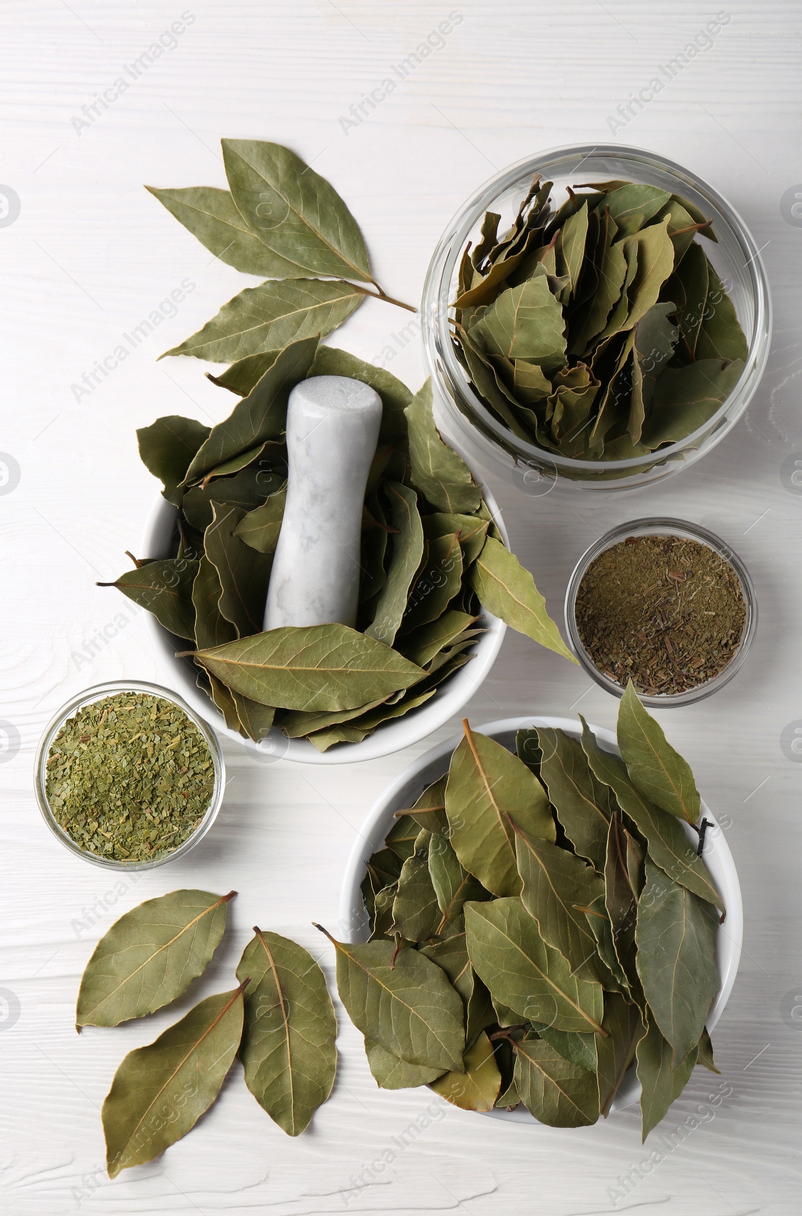 Photo of Whole and ground bay leaves on white wooden table, flat lay