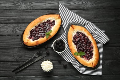 Photo of Delicious sweet cottage cheese pastry with cherry jam served on black wooden table, flat lay