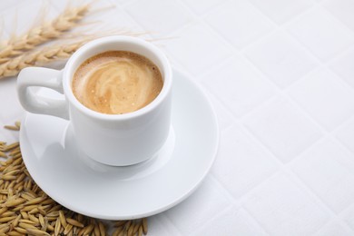 Photo of Cup of barley coffee, grains and spikes on white table, closeup. Space for text