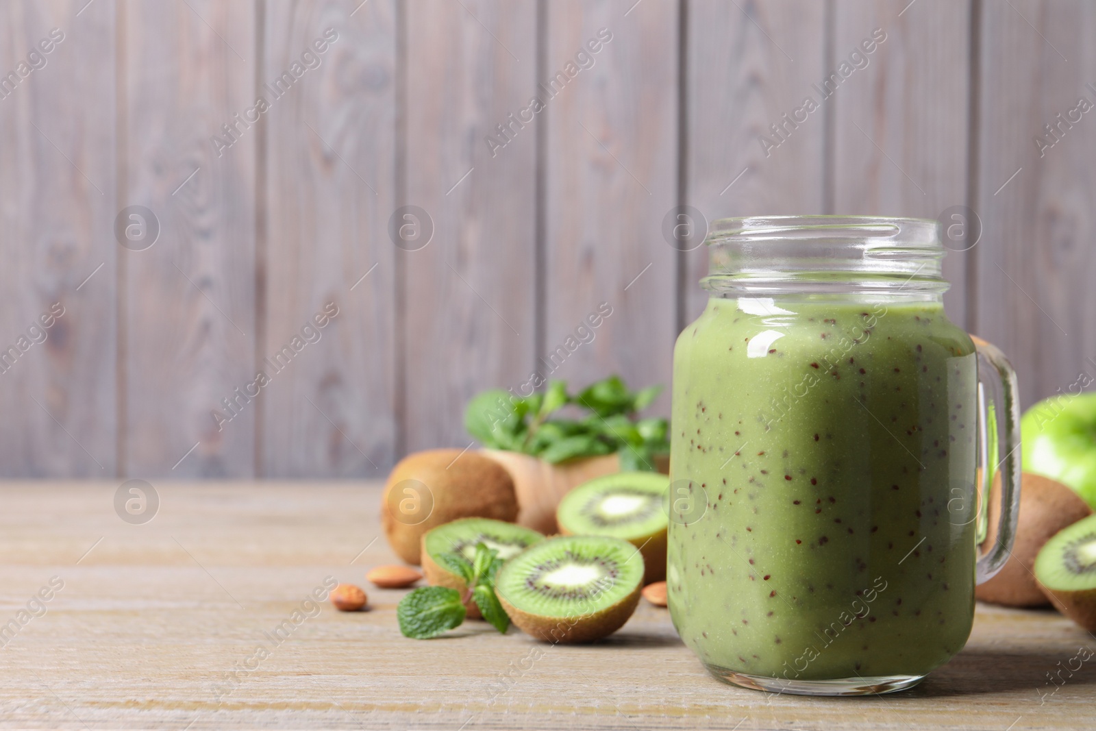 Photo of Delicious kiwi smoothie and fresh fruits on wooden table. Space for text