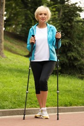 Photo of Senior woman with Nordic walking poles outdoors