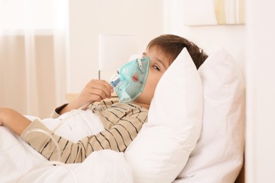 Boy using nebulizer for inhalation on bed at home