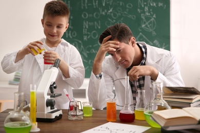 Teacher with pupil making experiment at table in chemistry class