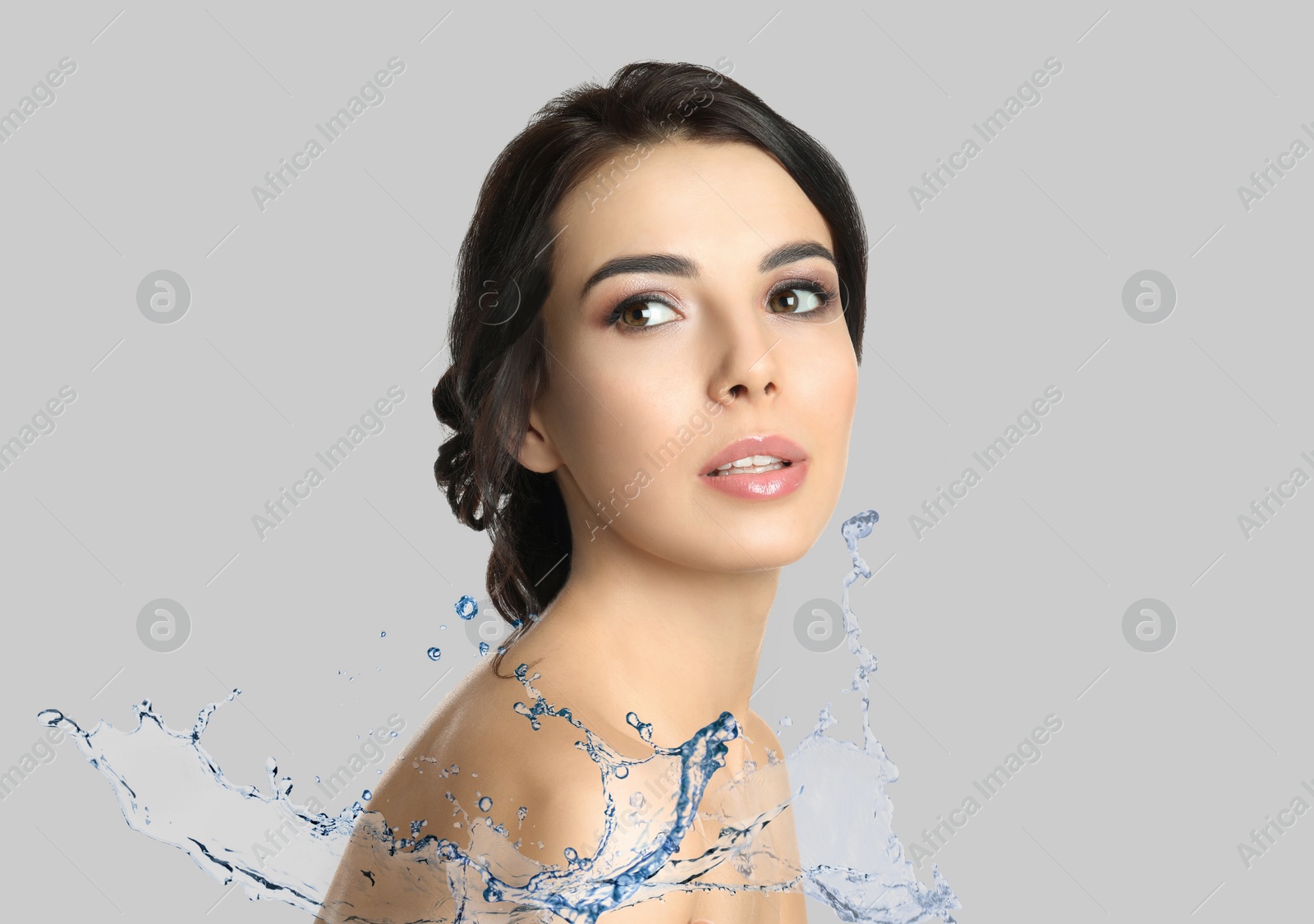 Image of Beautiful young woman and splashing water on light grey background. Spa portrait