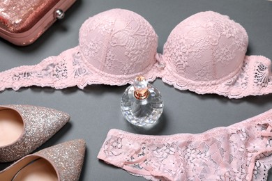Photo of Elegant light pink women's underwear, perfume, clutch and shoes on grey background
