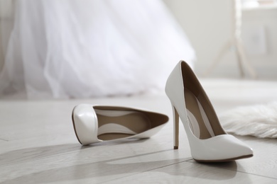 Photo of White wedding shoes on floor in room