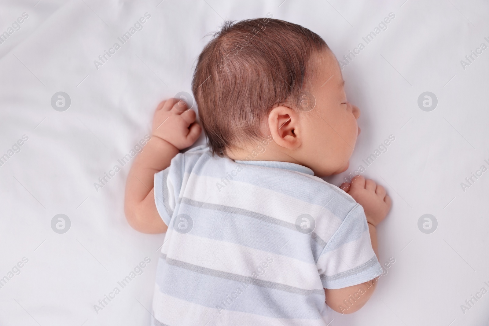 Photo of Cute newborn baby sleeping on white bed, top view