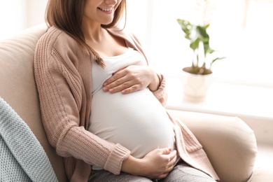 Young pregnant woman sitting on couch in living room