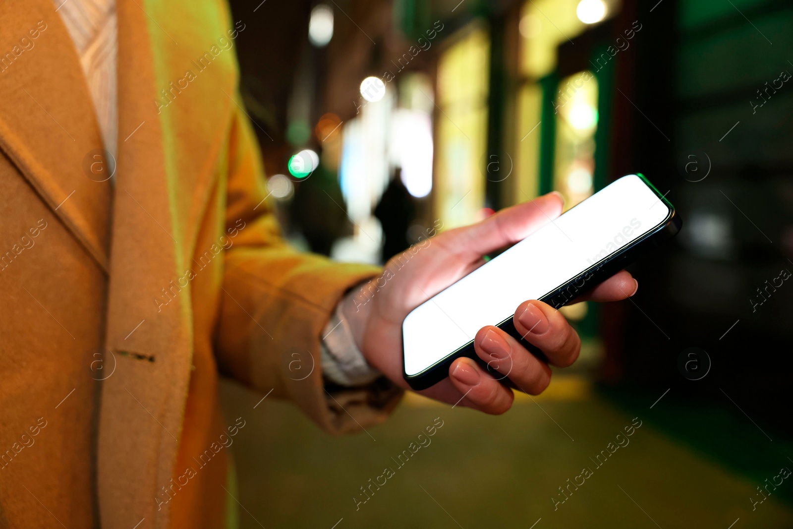 Photo of Woman with smartphone on night city street, closeup