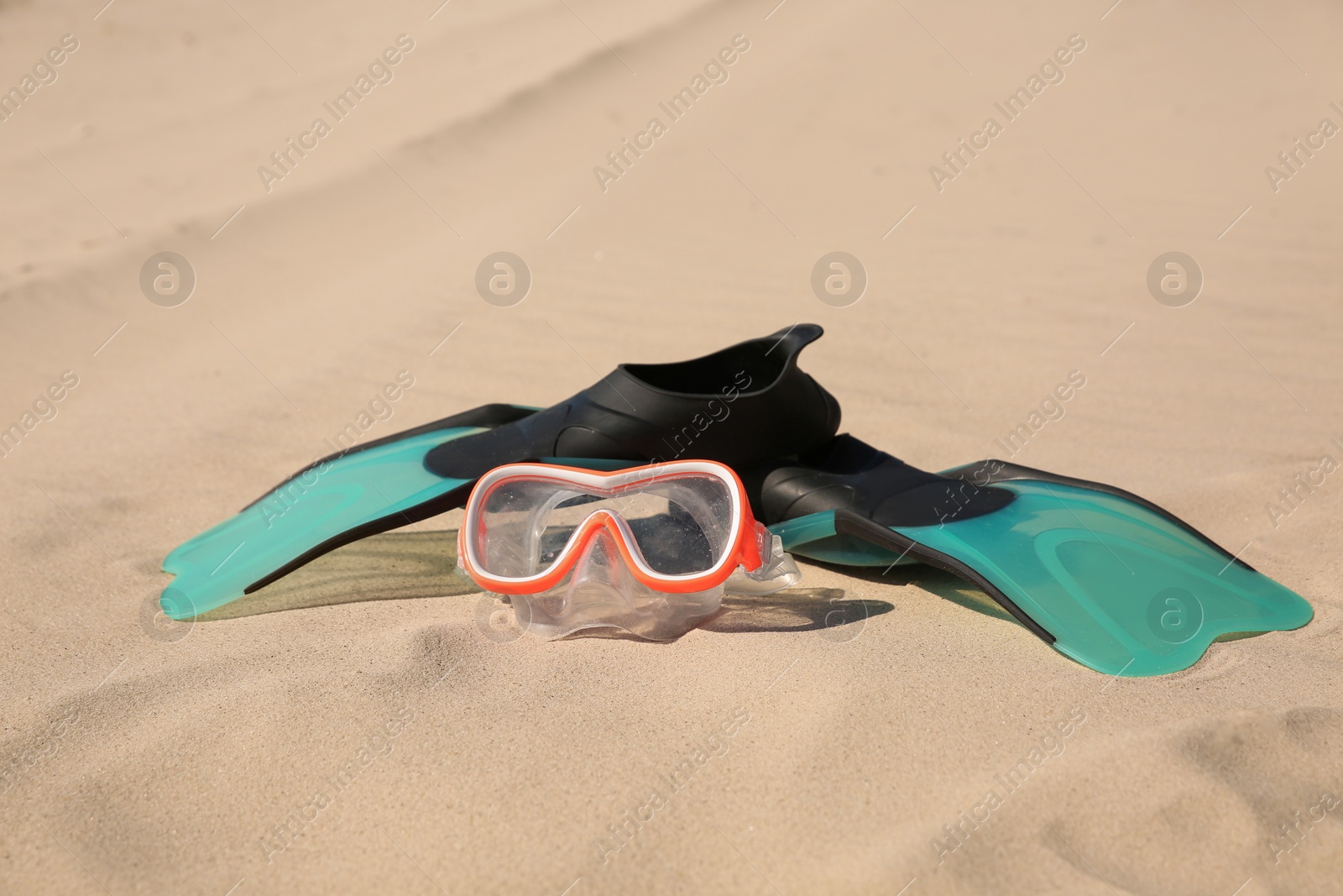 Photo of Pair of flippers and diving mask on sandy beach