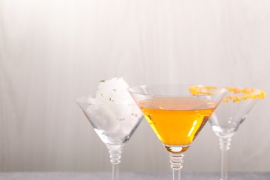 Photo of Cotton candy and cocktails in glasses on gray background, closeup. Space for text