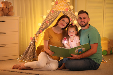 Photo of Family with flashlight reading book at home