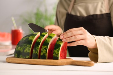 Photo of Woman cutting delicious watermelon at white wooden table indoors, closeup