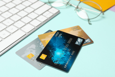 Photo of Credit cards near computer keyboard on light blue background