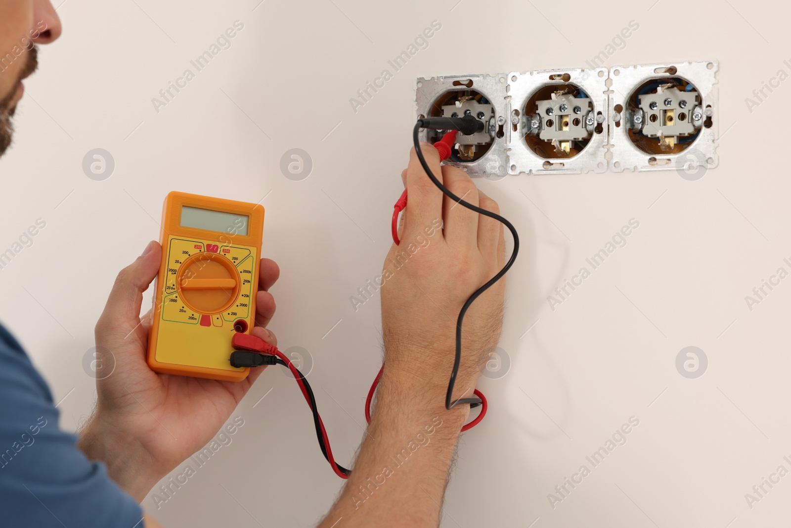 Photo of Electrician with tester checking voltage indoors, closeup