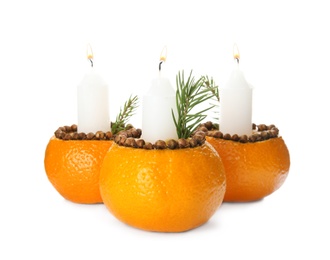Candles in tangerine peels as holders on white background