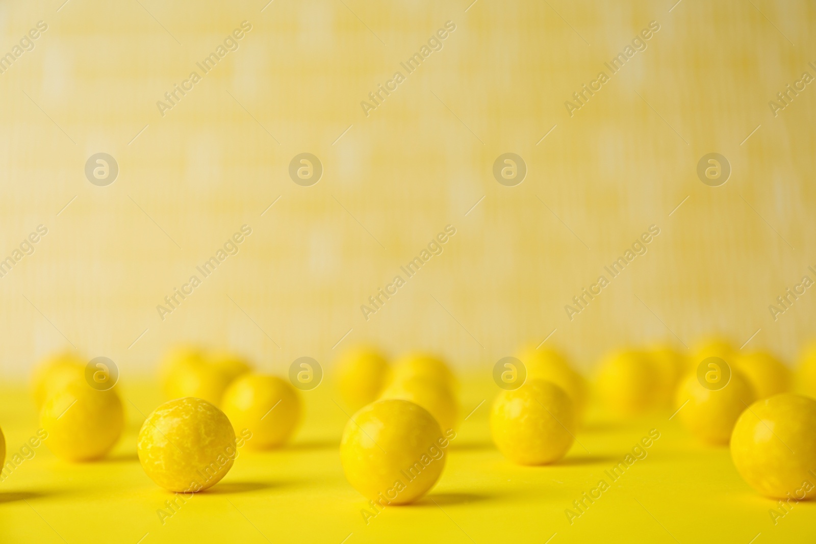 Photo of Delicious lemon chewing gums on yellow table