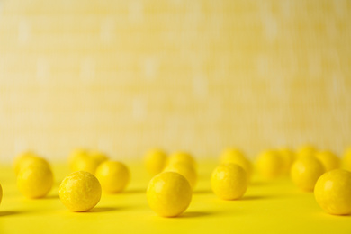 Photo of Delicious lemon chewing gums on yellow table