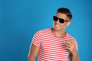 Photo of Handsome man wearing sunglasses on blue background