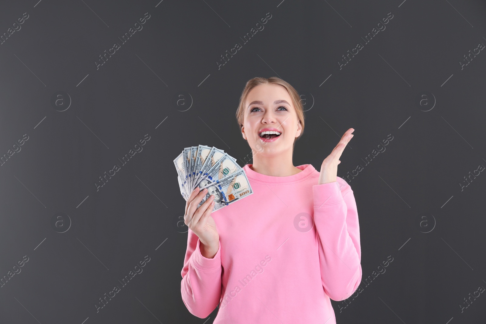 Photo of Portrait of emotional young woman with money on grey background