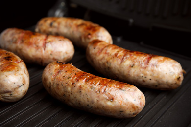 Photo of Cooking delicious sausages on modern grill, closeup