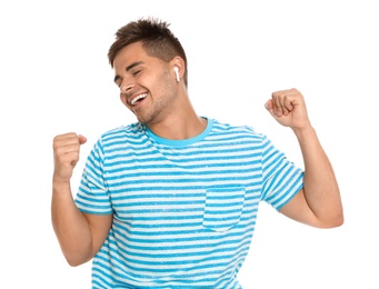 Happy young man listening to music through wireless earphones on white background