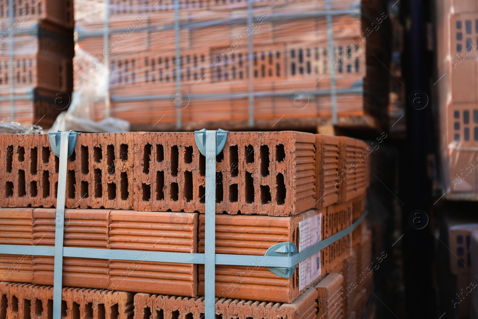 Photo of Pile of red bricks outdoors, closeup. Building materials wholesale