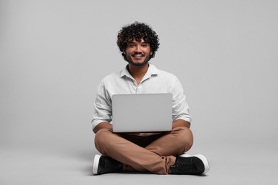 Photo of Smiling man with laptop on light grey background