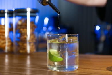 Photo of Pouring vodka into glass on wooden counter in bar
