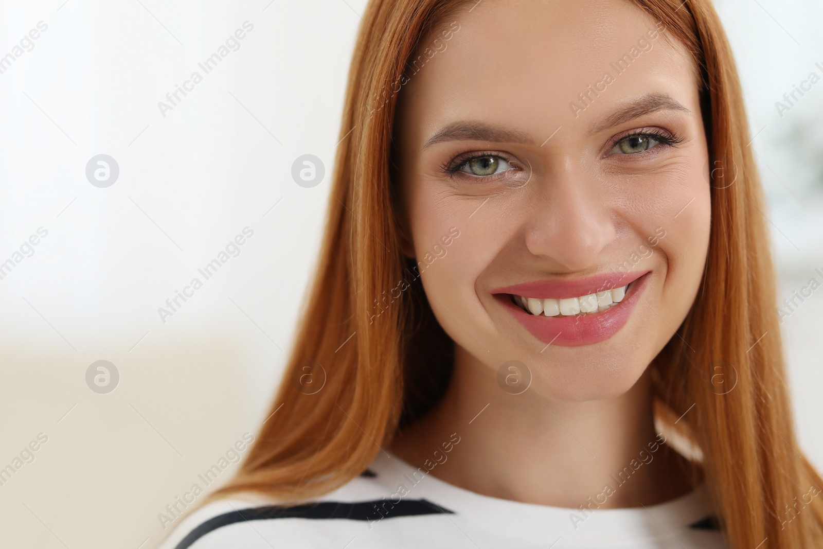 Photo of Portrait of beautiful young woman with red hair indoors. Attractive lady smiling and looking into camera. Space for text