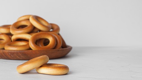 Tasty dry bagels (sushki) and plate on white textured table, space for text